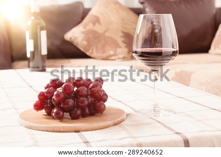 Glass of red wine with red globe grapes  photographed on the table with natural light