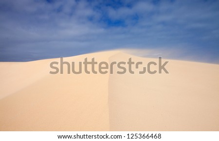 sand and sky dunes abstract, edge of the dune blurred by flying sand