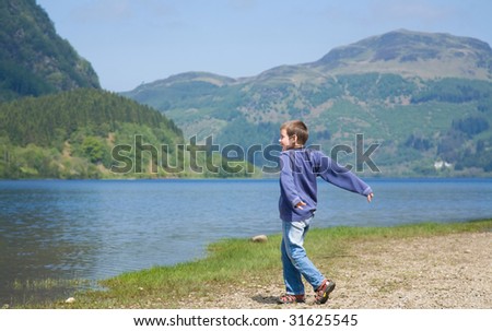 Little boy is throwing stones in the water, Loch Lubnaig