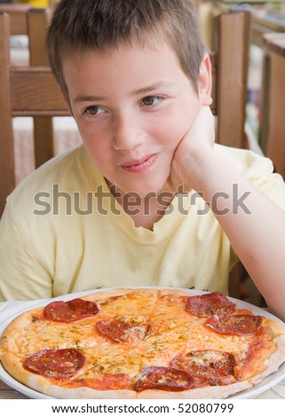 it\'s my  pizza - cute little caucasian boy waiting till he can start eating over his salami pizza in a restaurant