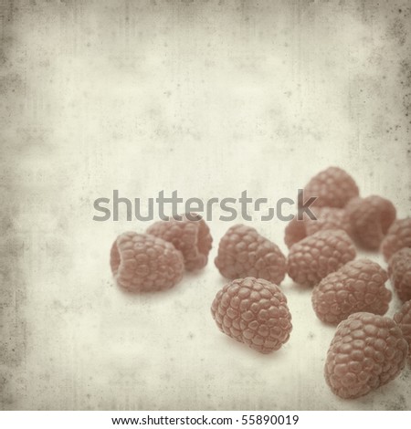 textured old paper background with fresh ripe red raspberries
