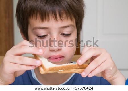 eating sandwich - small caucasian boy finishing white bread sandwich crust;
