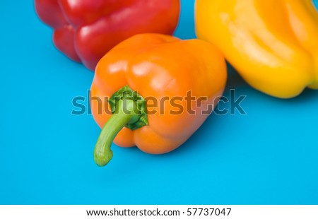 orange, red and yellow sweet peppers on bright blue plastic chopping board surface