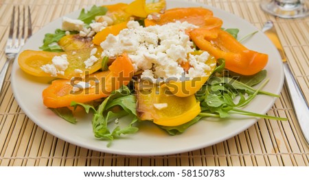summer light meal -- fried sweet pepper with; garlic and crumbled feta cheese; on a bed of rocket salad