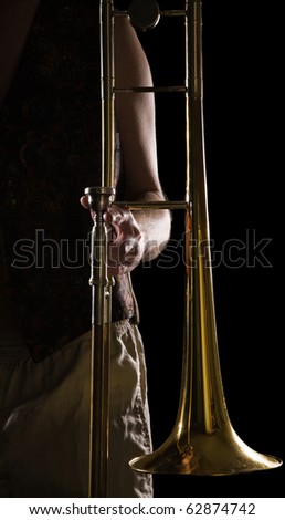 man holding a trombone; strong contrasting side-light; color version