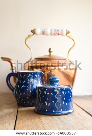 old-fashioned tea - old dark blue ceramic sugar pot and milk jug, copper kettle in the background