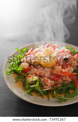 freshly made steaming hot seafood paella served on a bed of wild rocket salad