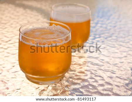 two beers served outside in the shade of textured glass table