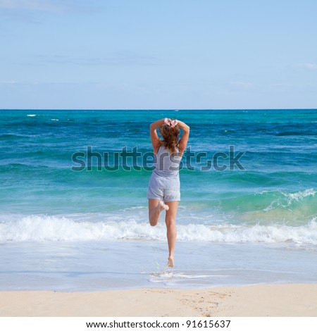jumping by an ocean - happy tanned middle-age woman jumping in the shallow water