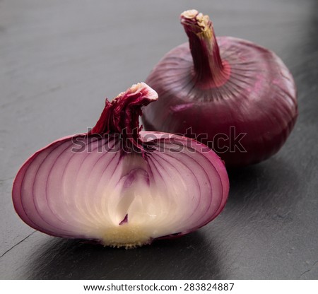 flat red onion cut in half on black slate stone surface