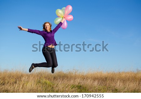 Smiling girl jumping with baloons. Outdoor shot.