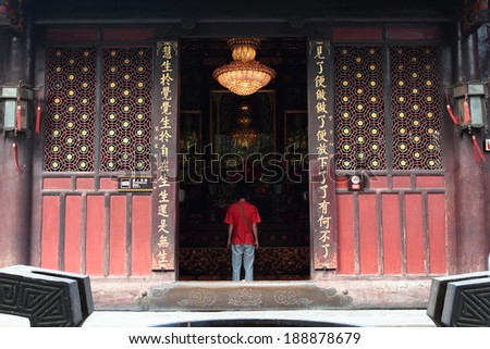 A boy wearing a red dress to pay tribute to the Buddha in the temple to pray