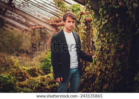 Fashionable young man in black jacket outdoor in a park