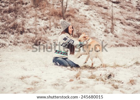 beautiful young woman smiling and playing with the dog in the winter park