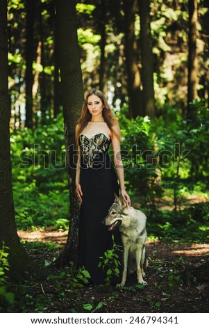portrait of a girl in a dark dress with a dog in the forest