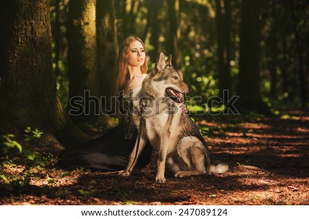 girl with a dog-wolf sitting in the dark forest