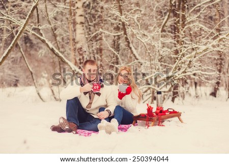 Positive couple drinking tea in a snowy forest