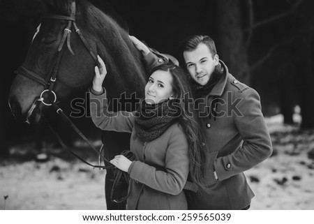 Happy people outdoors with horse and couple in love. Black and white photo