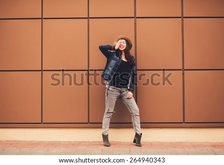 cheerful young woman full-length standing against a wall. copy-space