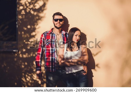 Portrait of a beautiful hipster couple. Positive guy in a shirt and sunglasses. Girl in t-shirt  against a vivid background outdoor