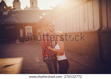 Positive couple walking along the streets in the summer sunny day. back light. looking at the camera