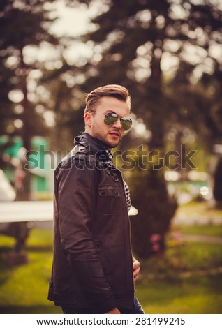 young stylish man with a beard walks in sunglasses outdoors