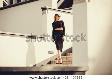 fashion outdoor photo of beautiful ladylike woman with long hair wearing elegant pencil skirt and posing in city