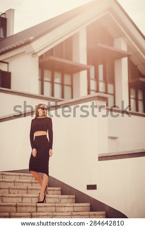 office woman dressed in strict black pencil skirt and top. looking away