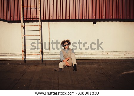 a young man with curly hair sits and stares into the camera. copy space