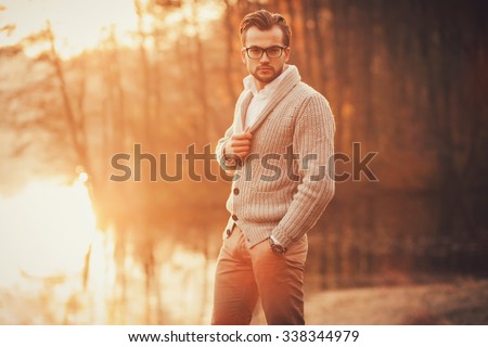 Trendy handsome man posing in autumn park alone
