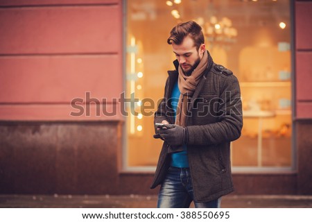 stylish man in a coat with a smartphone in the city. traveling