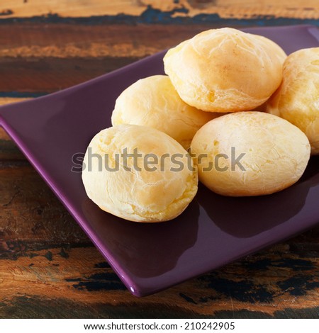 Brazilian snack cheese bread (pao de queijo) on purple plate on wooden table. Selective focus