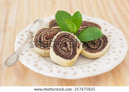 Bolo de rolo (swiss roll, roll cake) Brazilian chocolate dessert with fresh mint on white plate. Selective focus