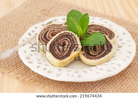 Brazilian chocolate dessert Bolo de rolo (swiss roll, roll cake) on white plate sackcloth. Selective focus