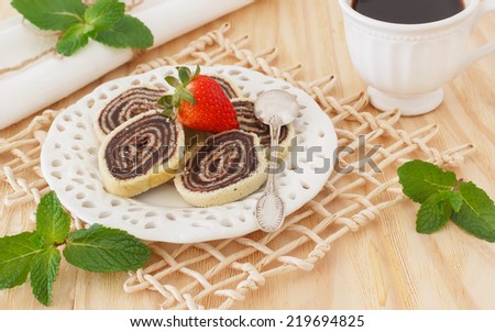 Bolo de rolo (swiss roll, roll cake) Brazilian chocolate dessert  with strawberry cup of coffee. Selective focus