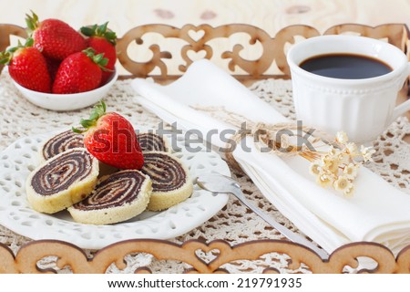 Brazilian chocolate dessert  Bolo de rolo (swiss roll, roll cake) with strawberry cup of coffee in tray. Selective focus