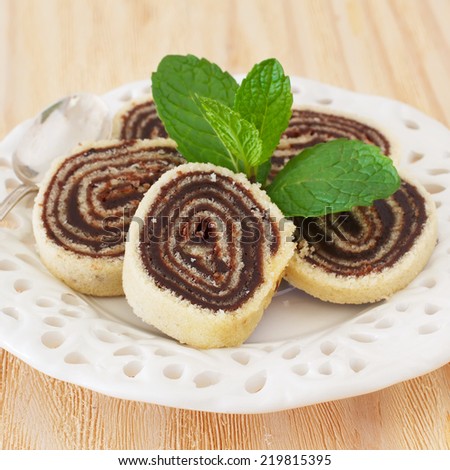 Bolo de rolo (swiss roll, roll cake) Brazilian chocolate dessert with mint on white plate. Selective focus