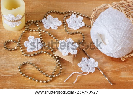 Idea for christmas decoration White crochet snowflakes on gift and candle on wooden table with copy space. Selective focus