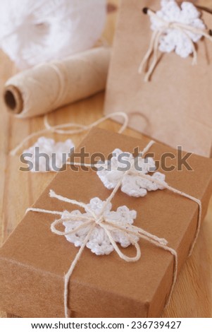 White crochet snowflakes for Christmas decoration of gift box and paper package. Selective focus