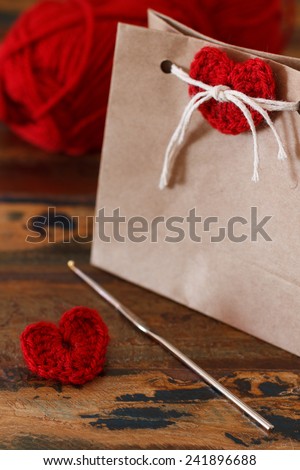 Saint Valentine\'s day decoration: handmade crochet red heart for gift paper package. Selective focus