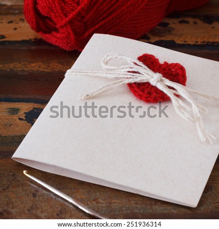 Handmade greetings card with crochet red heart for Saint Valentine\'s day. Selective focus
