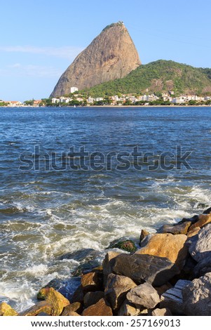 Mountain Sugarloaf from Park Flamengo with stones and waves in blue sea, Rio de Janeiro, Brazil