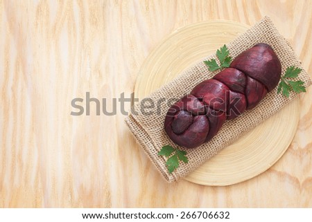 Treccia - homemade braided Mozzarella cheese marinated in red wine on sackcloth on wooden cutting board on table. Selective focus.  Copy space
