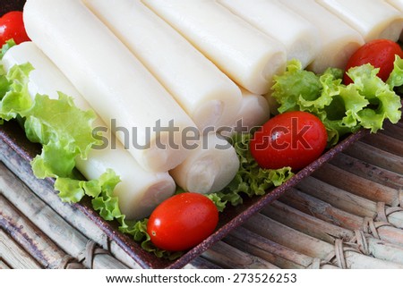 Closeup of Heart of palm (palmito) with cherry tomato on brown plate on wooden board. Selective focus