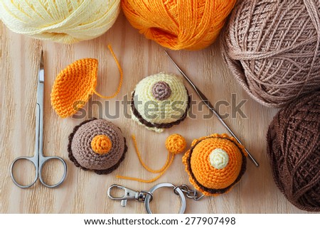 Making of handmade colorful crochet toys sweets (key ring) with skein on wooden table. Selective focus