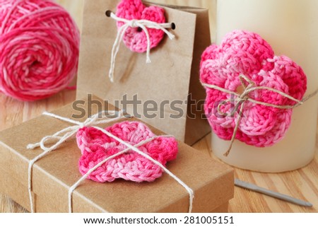 Handmade colorful crochet flowers and heart for decoration of gift and candle with skein on wooden table. Selective focus