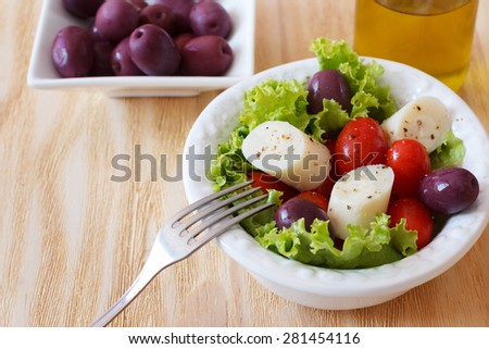 Fresh salad of heart of palm (palmito), cherry tomatos and olives on white plate. Selective focus