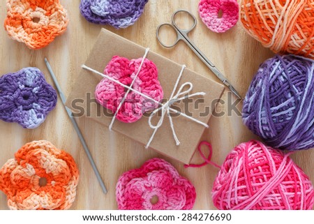 Handmade colorful crochet flowers for decoration of gift with skein on wooden table. Selective focus