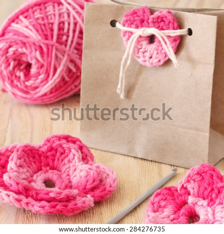 Handmade pink flowers, heart and bow for decoration of gift with skein on wooden table. Selective focus. Toning effect