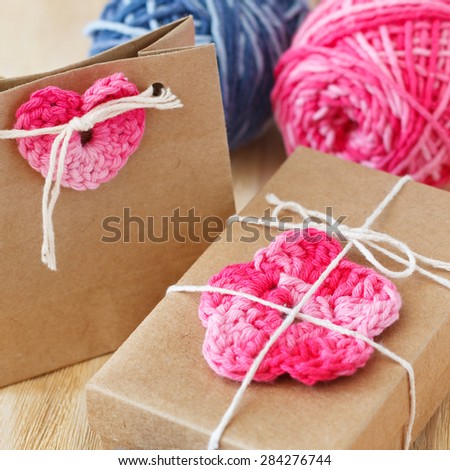 Handmade colorful crochet flowers and heart for decoration of gift with skein on wooden table. Selective focus